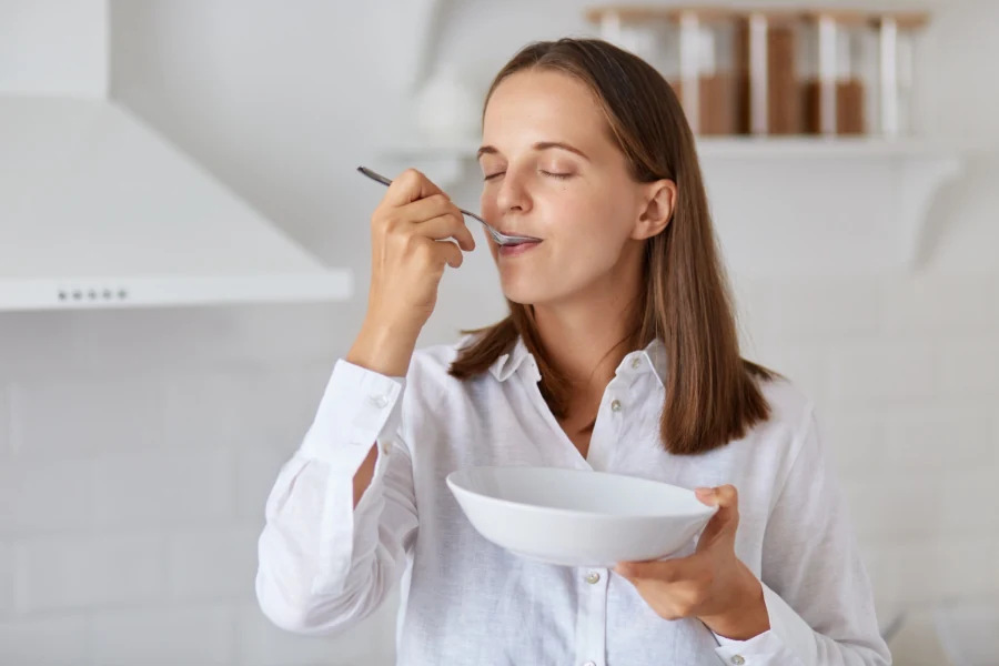 Mulher saboreando uma refeição leve na cozinha